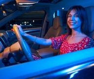 Cheerful young woman driving car at night